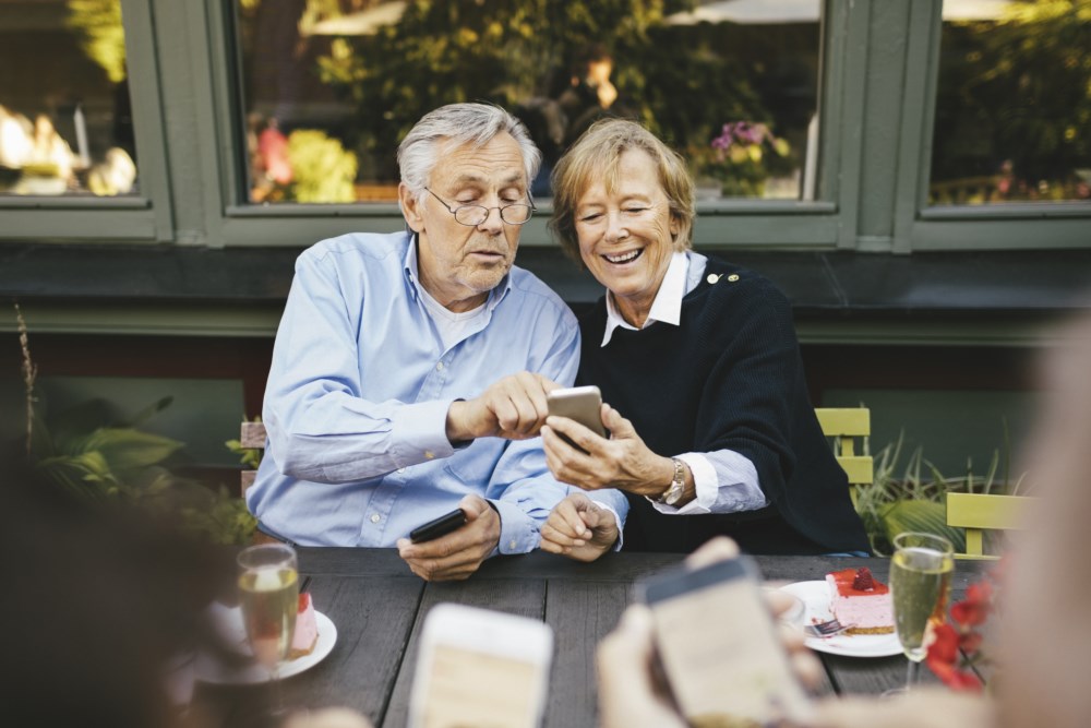 Et eldre par som smiler og ser på en telefon
