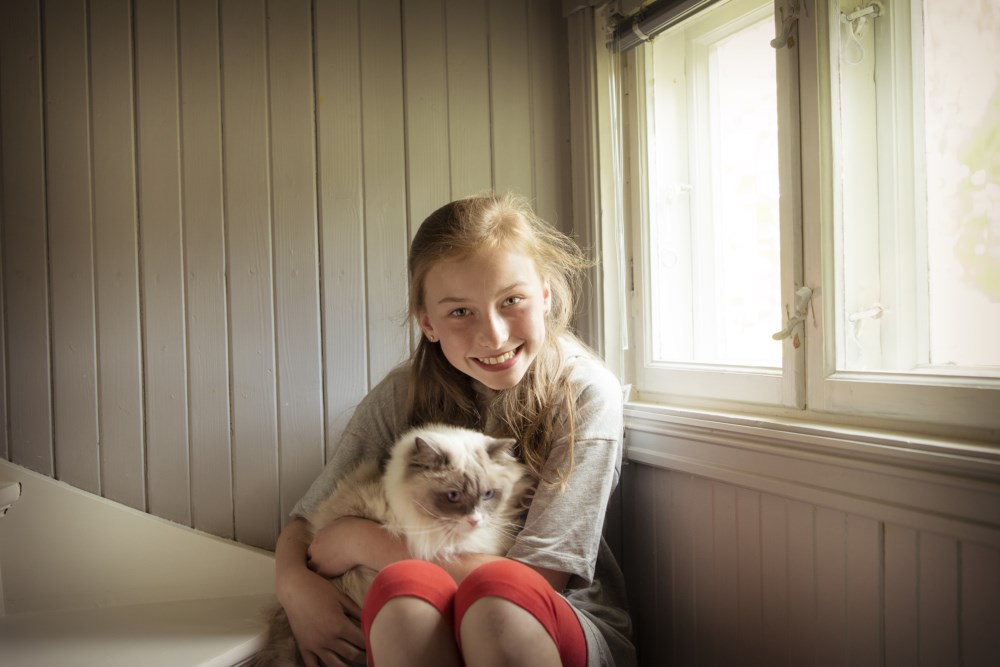 Smilende jente med katt på fanget