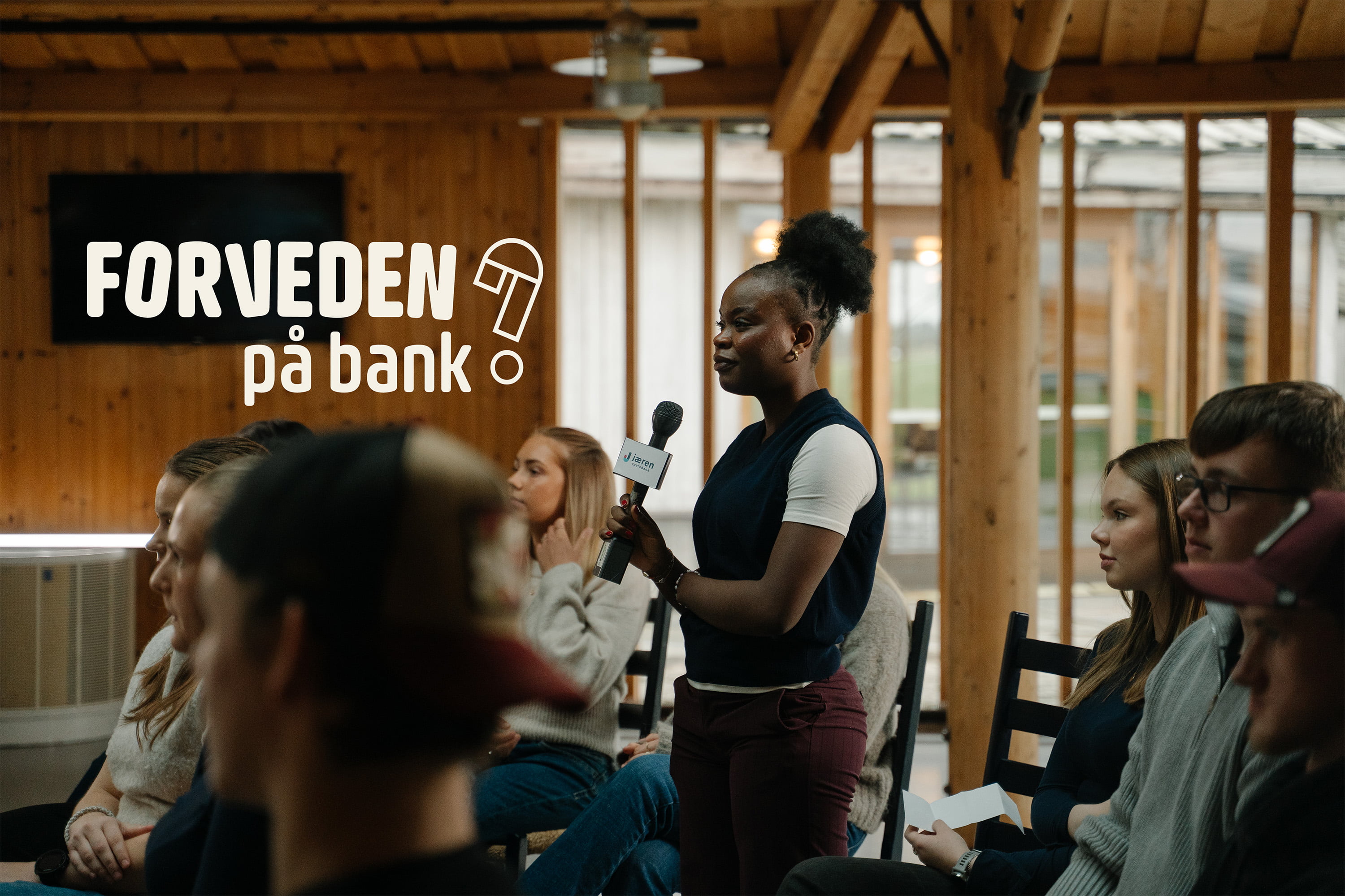 Ung kvinne står med Jæren Sparebank mikrofon og stiller spørsmål om bank til UNG-rådgivere