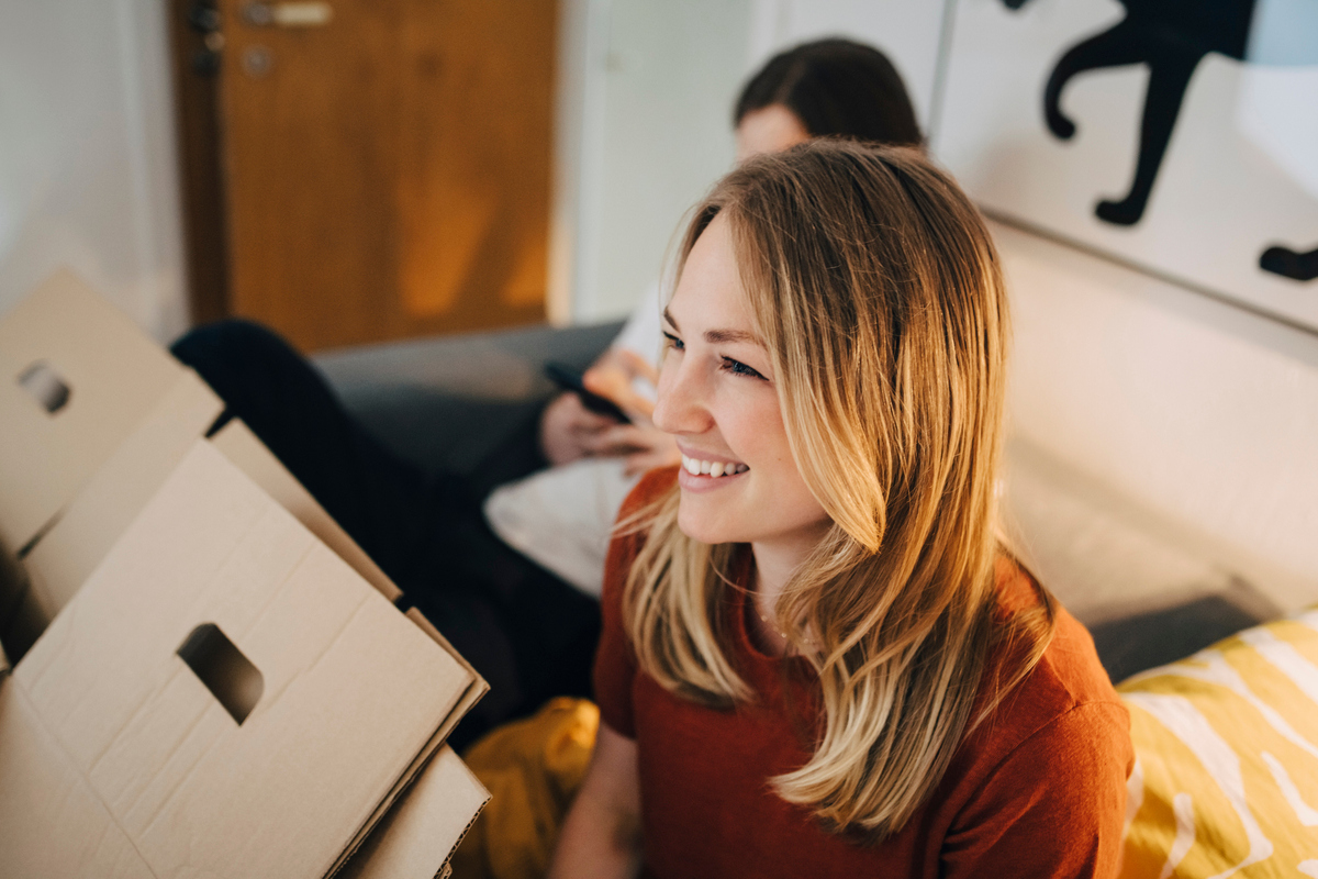 Smilende jente som sitter blant flytteesker